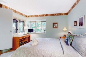 A bedroom with a bed, a desk, a chair, a window, and a door.