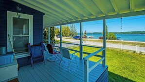 Ein überdachter Balkon mit Blick auf ein Gewässer, ein Stuhl und ein Fenster.
