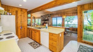 Una cucina con armadietti in legno, un camino in pietra, un'isola grande e vista sull'esterno.