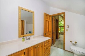 A bathroom with a wooden vanity, a large mirror, and a white toilet. - Rustic dream home w/ lake views, wraparound deck, & wood-burning fireplace (Frankfort)