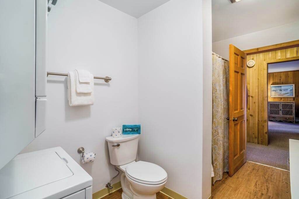 A bathroom with a toilet, a towel rack, and a shower area.
