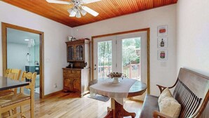 A dining area with a wooden table and chairs, a ceiling fan, and a view through a glass door to the outside. - Dog-friendly home in the perfect location with enclosed yard, streaming, & W/D (Union Pier)