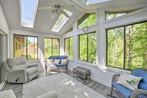 A spacious room with large windows, a ceiling fan, and a blue sofa. - Serene Home with Fire pit, Gas Grill, WIFI & Close to Beach (Three Oaks)