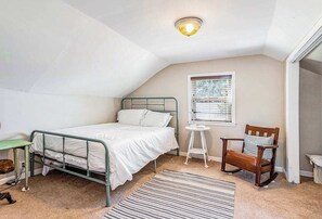 A bedroom with a single bed, a small table, a chair, a window with blinds, and a ceiling light fixture. - Quaint, budget-friendly home walking distance to town with grill - dog-friendly (Three Oaks)
