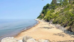 En strand med klart vatten, sandstrand och klippiga utskjutande partier.