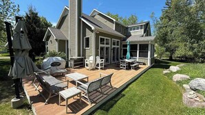 Ett tvåvåningshus med en veranda, utemöbler och en grill.