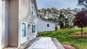Una casa con terraza de madera, garaje y césped.