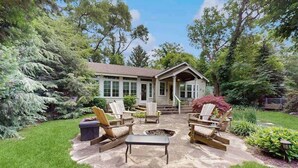 Ein Haus mit einer Terrassenanlage, die Gartenmöbel und eine Feuerstelle bietet.