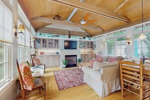 Ein geräumiges Wohnzimmer mit Kamin, Holzboden und großen Fenstern.