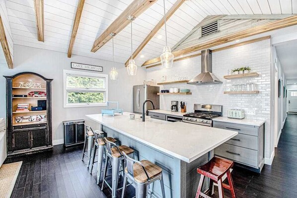 A modern kitchen with a large island, bar stools, and a view of Lake Michigan. - Fully-renovated lakefront home with beach cabana, association beach, & firepit (Lakeside)