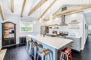 A modern kitchen with a large island, bar stools, and a view of Lake Michigan. - Fully-renovated lakefront home with beach cabana, association beach, & firepit (Lakeside)