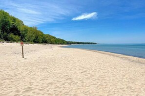 A sandy beach with a clear sky and a signpost. - Fully-renovated lakefront home with beach cabana, association beach, & firepit (Lakeside)