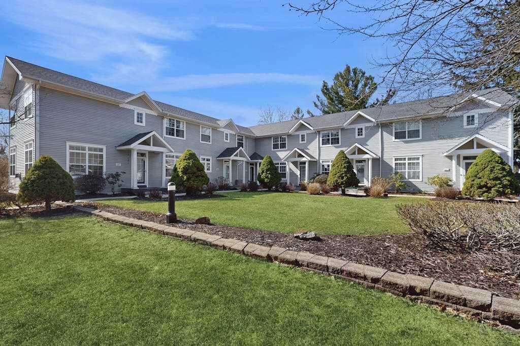A row of two-story houses with a well-maintained lawn and trimmed bushes.