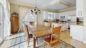 Una cocina amplia con armarios blancos, una mesa de comedor de madera y una araña.