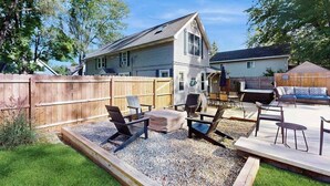 Ein Garten mit einer Holzdiele, Gartenmöbeln und einem Haus im Hintergrund.