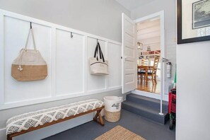 A hallway with a bench, a wall-mounted bench, a door leading to a dining area, and a trash bin. - Enjoy a scenic getaway, a relaxing hot tub, and seasonal comfort. (New Buffalo)