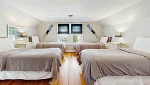Ein Schlafzimmer mit zwei Betten, einem Fenster mit Jalousien, einem Deckenventilator und einem Nachttisch mit Lampe.
