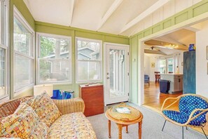 A cozy living room with a sofa, chairs, a small table, and a kitchen area visible through an open door.