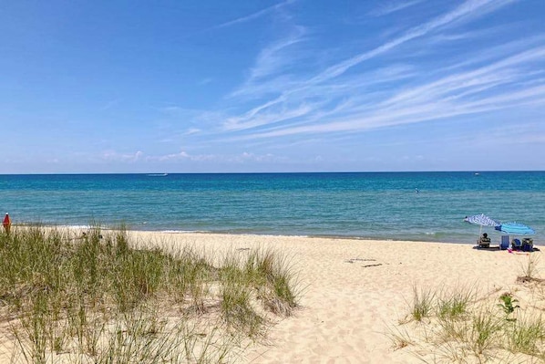 A beach with clear skies, a sandy shore, and a few beach umbrellas.