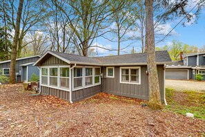 A small, single-story cabin with a sloped roof, large windows, and a covered porch area.