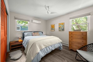 A bedroom with a bed, dresser, chair, and a ceiling fan. - Steps to Ridge Road Beach Renovated Home w/ Private Hot Tub, Firepit & Porch (Grand Beach)