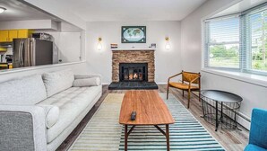 Ein modernes Wohnzimmer mit Kamin, Sofa, Couchtisch und Essbereich.