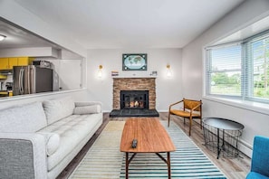 Ein modernes Wohnzimmer mit Kamin, Sofa, Couchtisch und Essbereich.