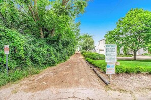 A dirt path leading to a building with a signboard listing beach rules. - Steps to Ridge Road Beach Renovated Home w/ Private Hot Tub, Firepit & Porch (Grand Beach)