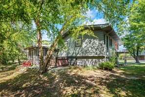 A stone house with a covered porch and a hot tub in the yard. - Steps to Ridge Road Beach Renovated Home w/ Private Hot Tub, Firepit & Porch (Grand Beach)