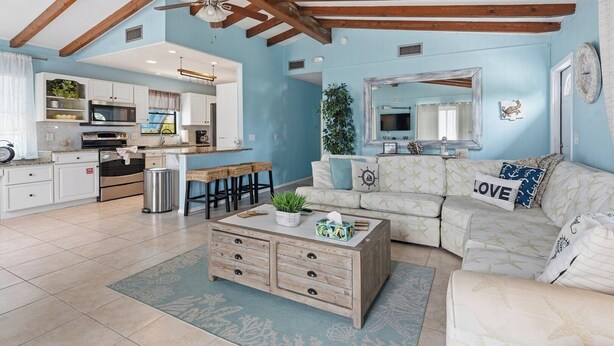 A spacious living area with a kitchen, a wooden ceiling, and a large mirror.