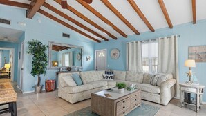 A living room with a sectional sofa, wooden coffee table, and a dining area with a table and chairs.