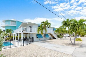 A two-story building with a balcony, a pool, and palm trees. - Blue Lagoon 2bed/2bath with private pool - no dockage (Marathon)