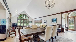 A spacious dining area with a large wooden table, multiple chairs, and a chandelier. - Golf Front Home with Course View, WiFi, Patio & Grill (Benton Harbor)