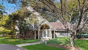 A stone house with a large arched window, a front porch, and a well-maintained lawn. - Golf Front Home with Course View, WiFi, Patio & Grill (Benton Harbor)