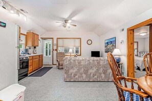 A compact living space with a kitchenette, a sofa, a dining table, and a ceiling fan.