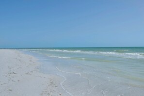 Ein Strand mit klarem Wasser und einem weiten, sandigen Ufer.