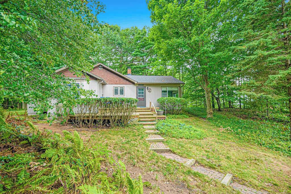 Une maison avec un jardin devant, un escalier en bois et un potager.