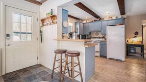 Una cocina con una isla central, taburetes de bar y un refrigerador.