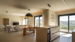A modern kitchen with a central island, dining area with chairs, and large windows offering a view. - Designer House Laloma (Málaga)