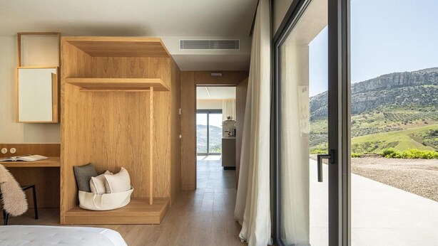 A modern hotel room with a large window, a wooden built-in bench, a bed, and a desk. - Designer House Laloma (Málaga)