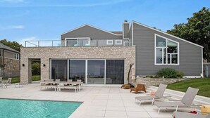 A modern house with a pool, outdoor seating, and a stone facade.