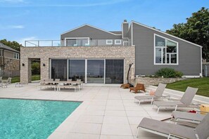 A modern house with a pool, outdoor seating, and a stone facade. - Large, dog-friendly lakefront home with private pool & hot tub, central AC & W/D (New Buffalo)