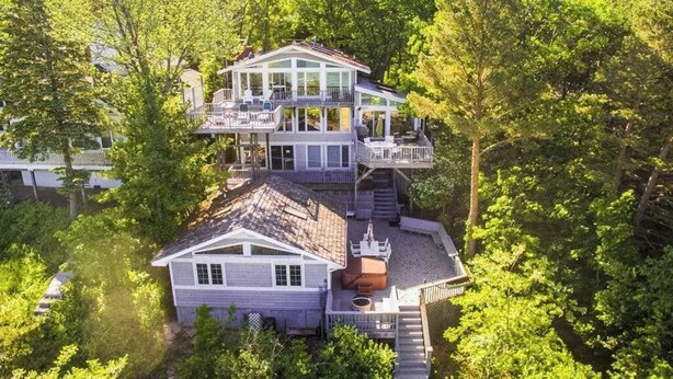 Una casa a più piani con una terrazza, circondata da alberi fitti.