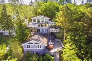 A multi-story house with a deck, surrounded by dense trees.