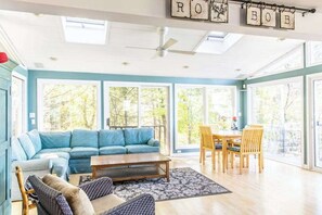 A spacious living room with a sectional sofa, a coffee table, and a dining area with chairs.