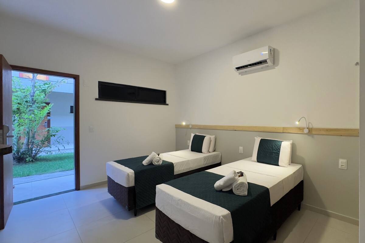 Habitación de hotel con dos camas, una ventana, equipo de aire acondicionado y vistas al exterior.