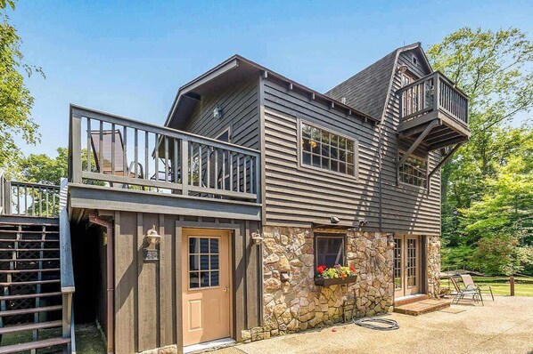 A two-story house with a stone foundation, a balcony, and a small porch.