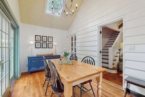 A dining area with a wooden table and chairs, a blue cabinet, and framed artwork on the wall. - Stunning Harbor County Home w/ Hot tub, Large yard, Near Beaches & Town. (Michiana)