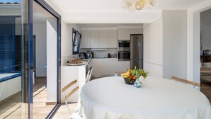 Une cuisine moderne avec des meubles blancs, un réfrigérateur en acier inoxydable et un coin repas doté d’une table ronde.