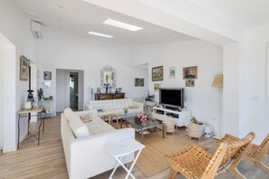 Ein modernes Wohnzimmer mit einer Couch, einem Couchtisch, einem Fernseher und Korbstühlen.